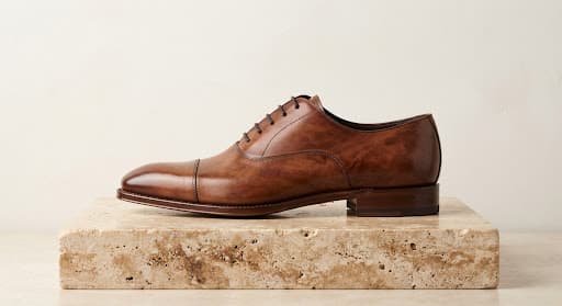 Cognac museum calf cap-toe oxford resting on a travertine plinth