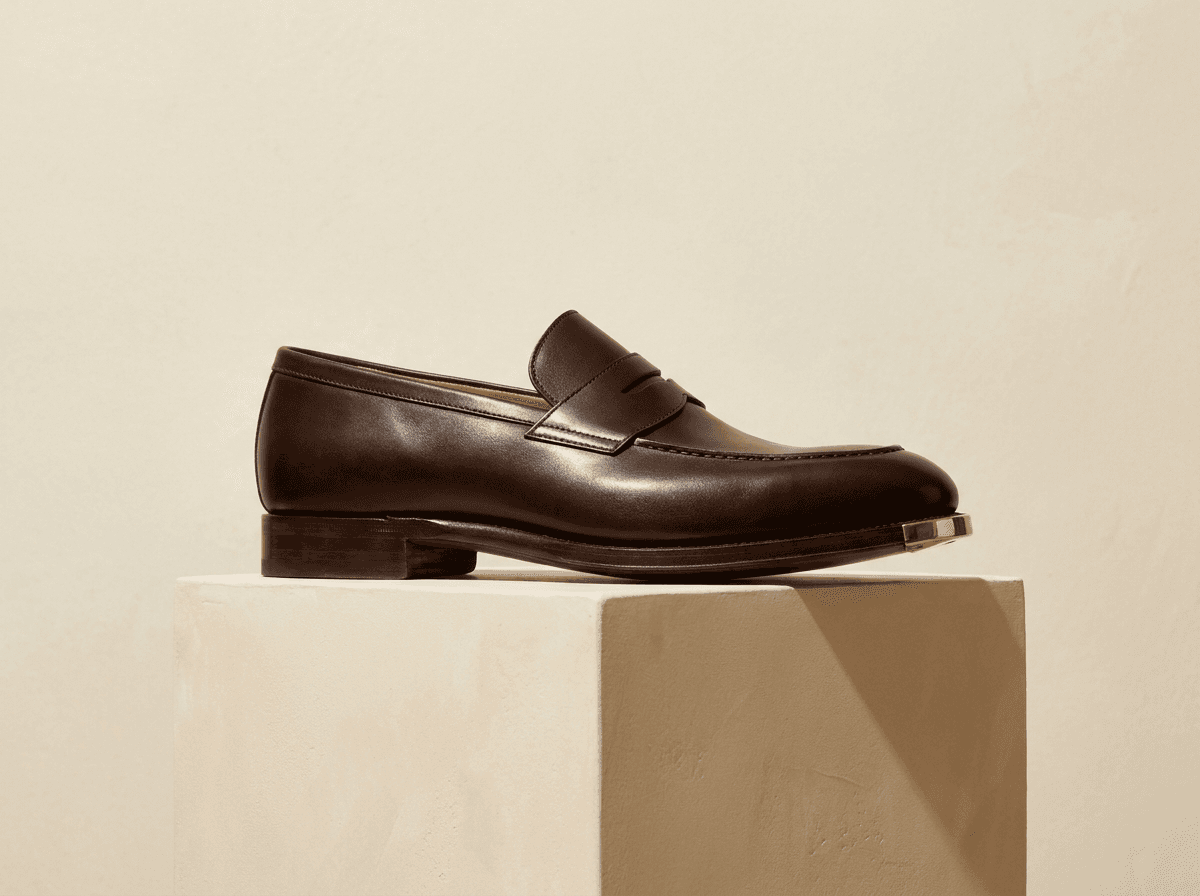 The Montgomery Penny Loafer in Espresso French Box Calf on stone pedestal
